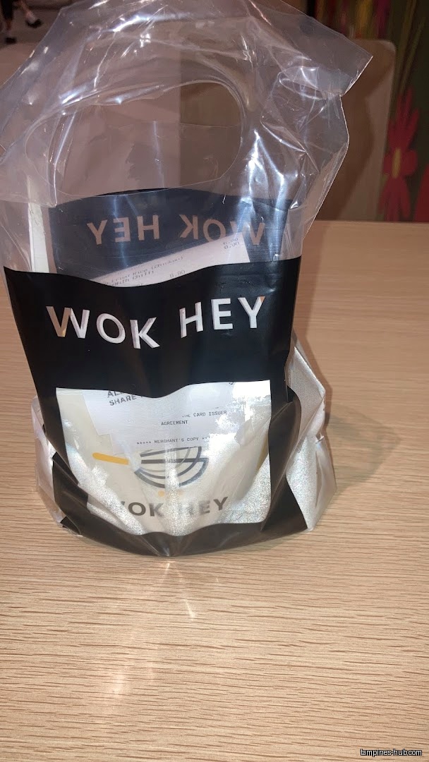 A WOK HEY bag with a receipt inside, sitting on a table.