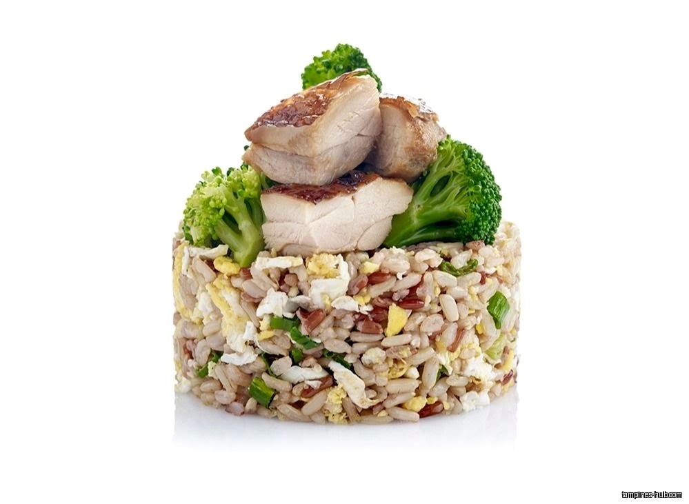 A serving of fried rice topped with chicken and broccoli.