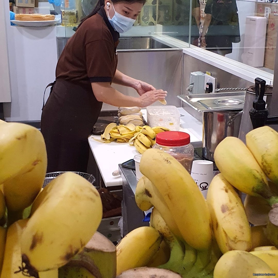 A worker prepares bananas in a kitchen area, with many bananas visible.