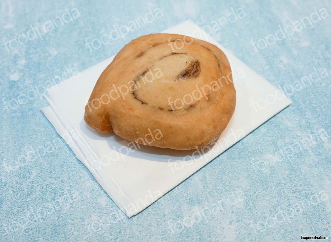 A cinnamon roll sits on a white napkin against a blue background.