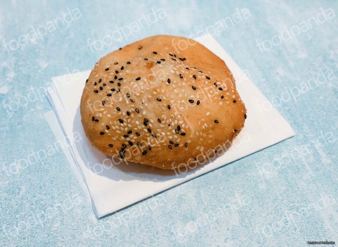 A sesame seed-covered pastry sits on a white napkin.