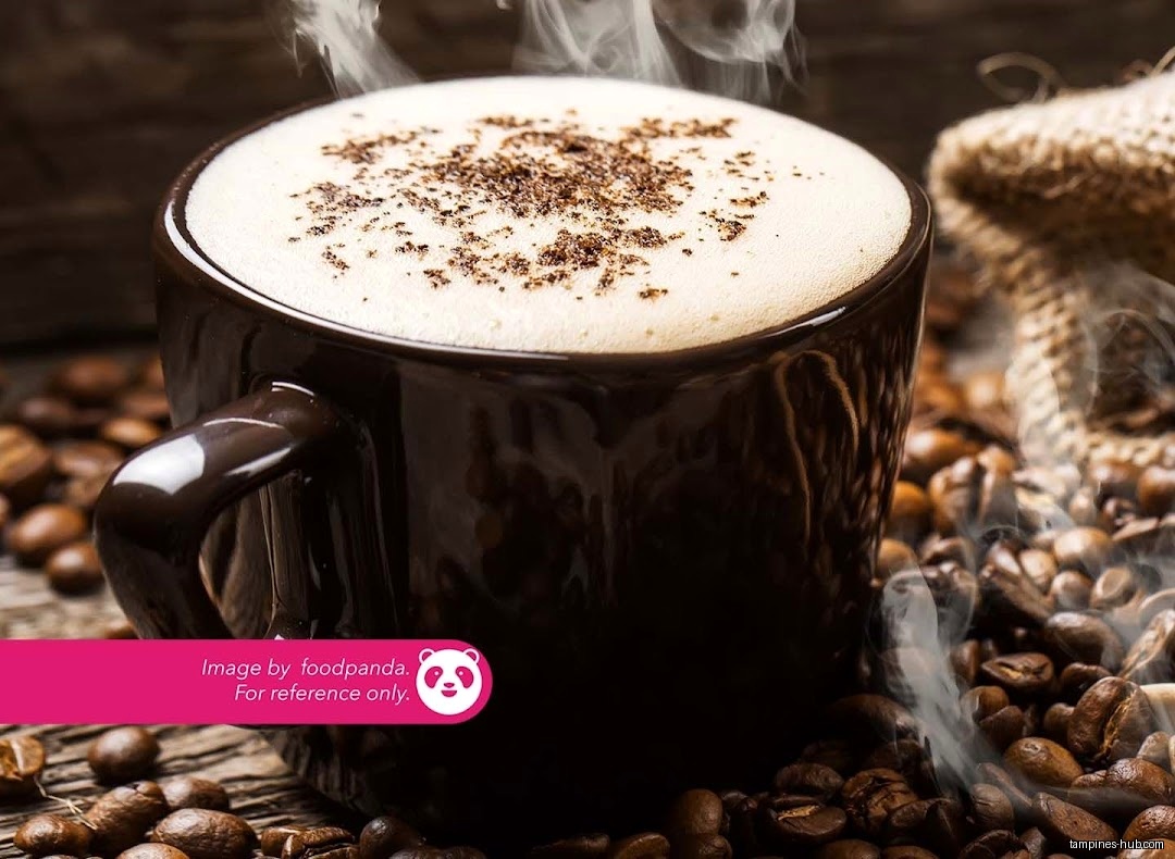 A steaming cup of coffee with foam and coffee beans around it.