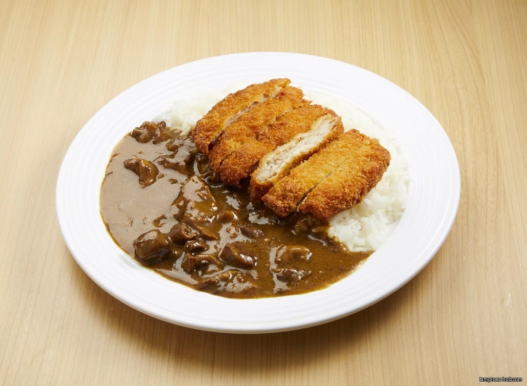 A plate of Japanese curry rice with tonkatsu on a wooden table.