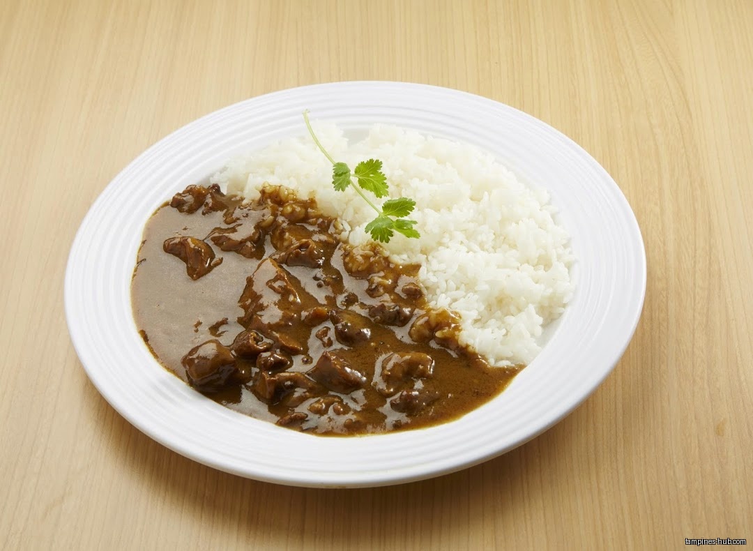 A plate of Japanese curry with rice and a sprig of parsley.
