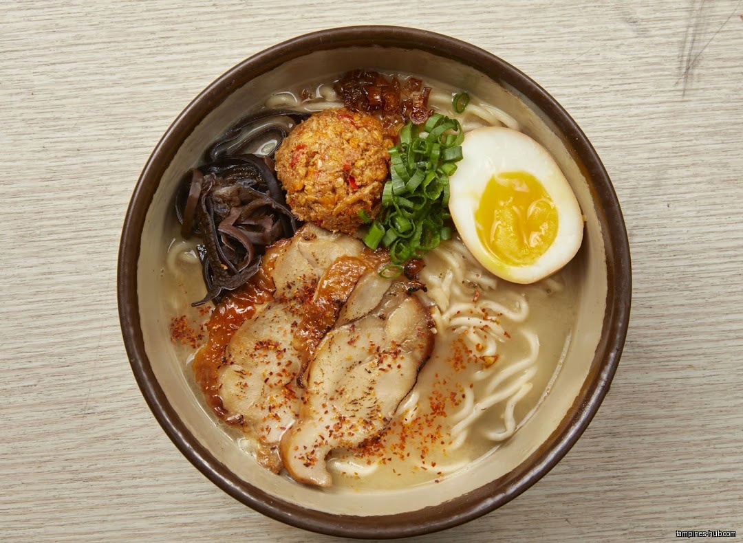 A bowl of ramen with pork, egg, and other toppings.