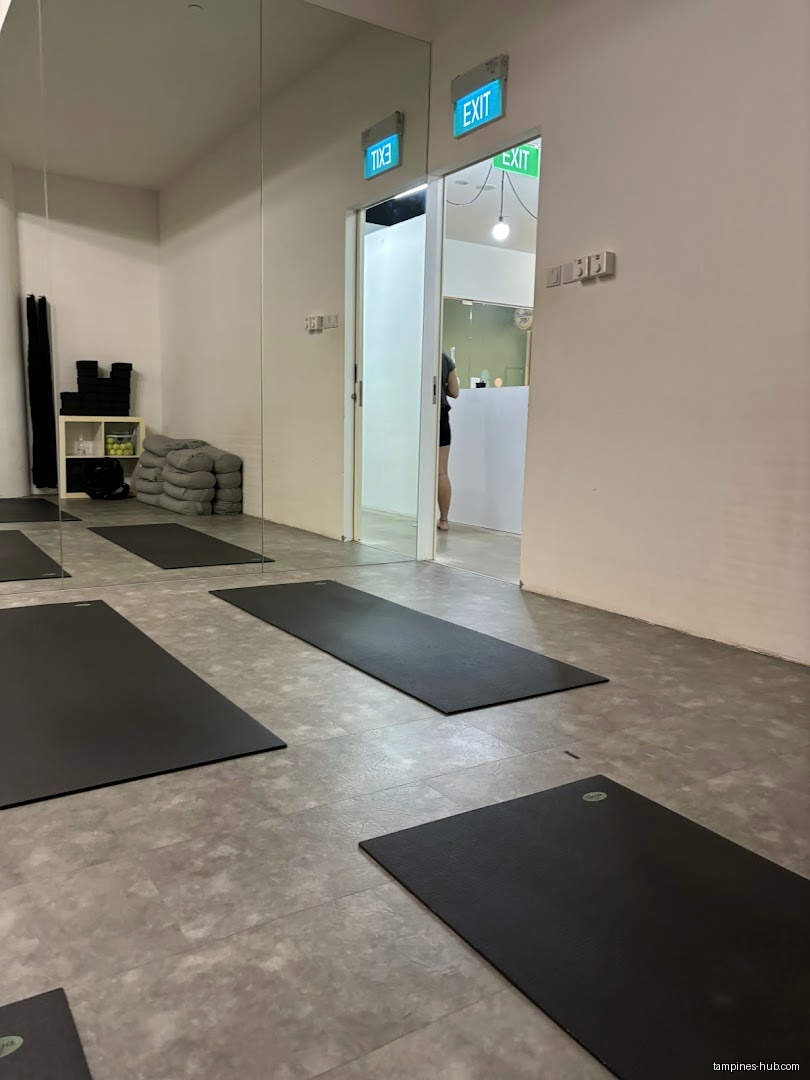 Yoga studio interior with mats, cushions, and a mirrored wall.