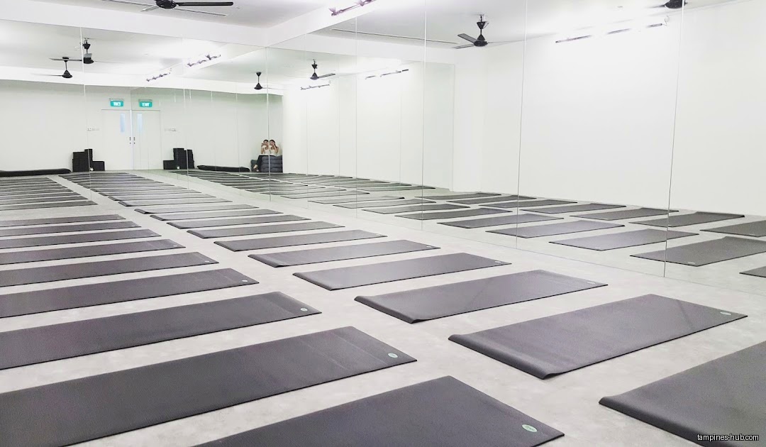 Yoga studio interior with mats neatly arranged on the floor and mirrors.