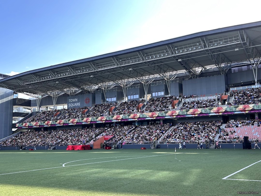 A stadium filled with people watching an event on a green field.