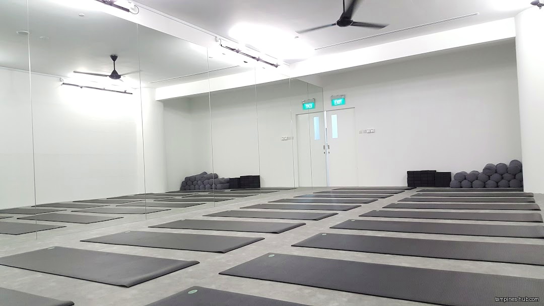 Yoga studio interior with mats, bolsters, blocks, and mirrors.