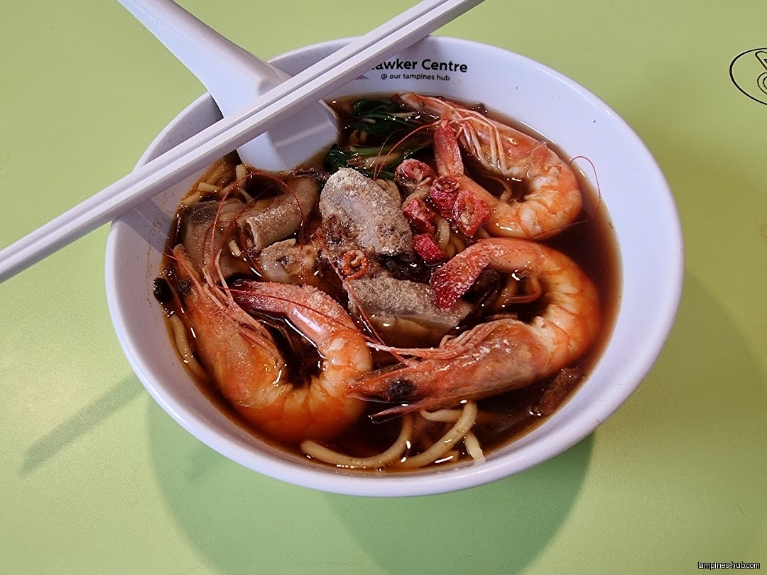 A bowl of prawn noodle soup with prawns, meat, and chopsticks.