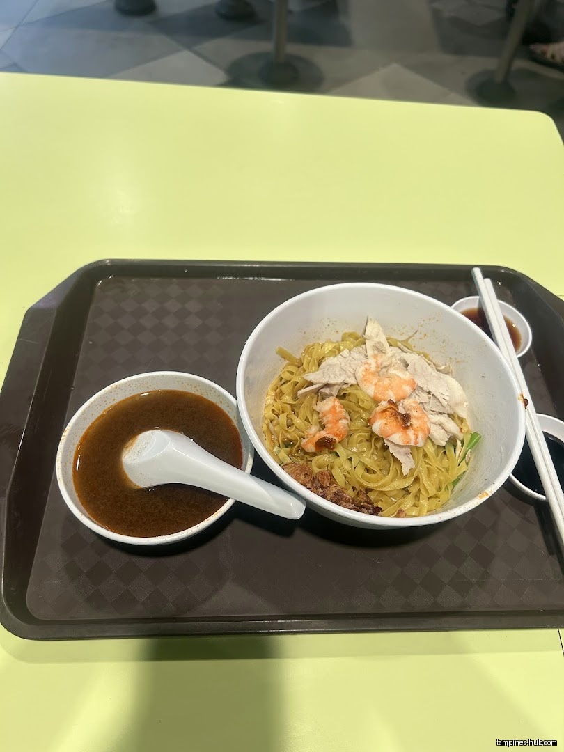 A bowl of prawn noodles with soup on a tray.