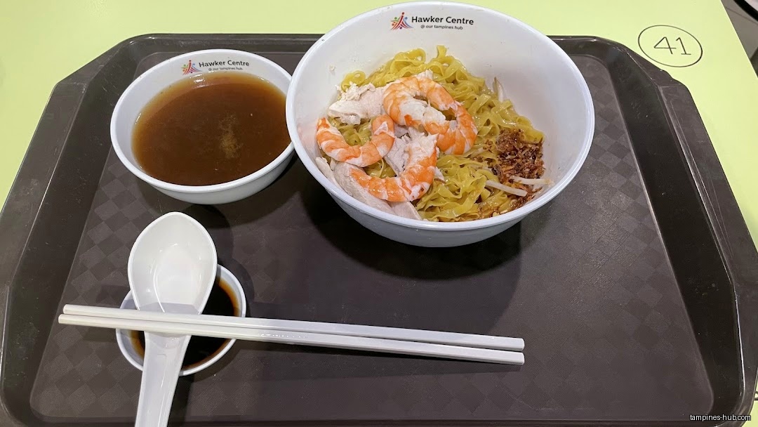 A tray with prawn noodles, soup, soy sauce, spoon, and chopsticks.