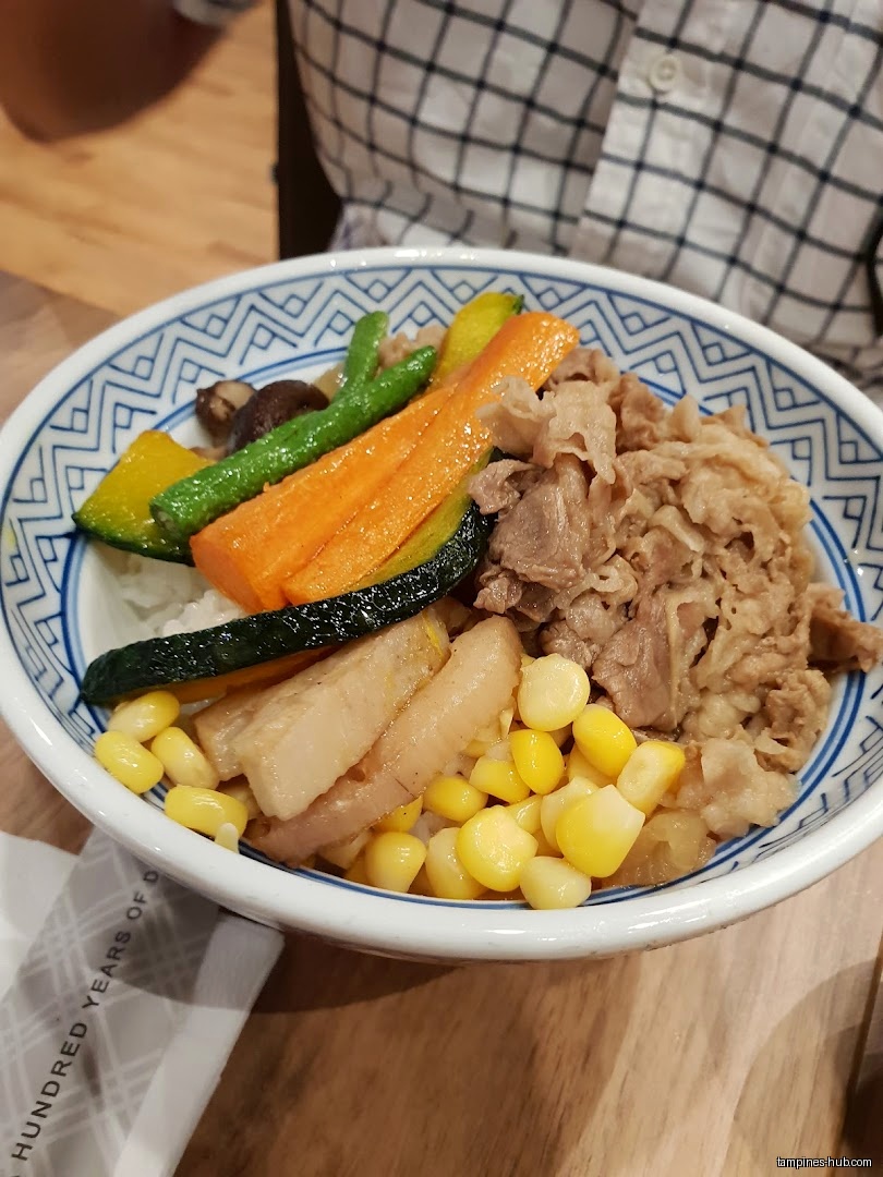 A bowl of Yoshinoya beef bowl with vegetables and corn.