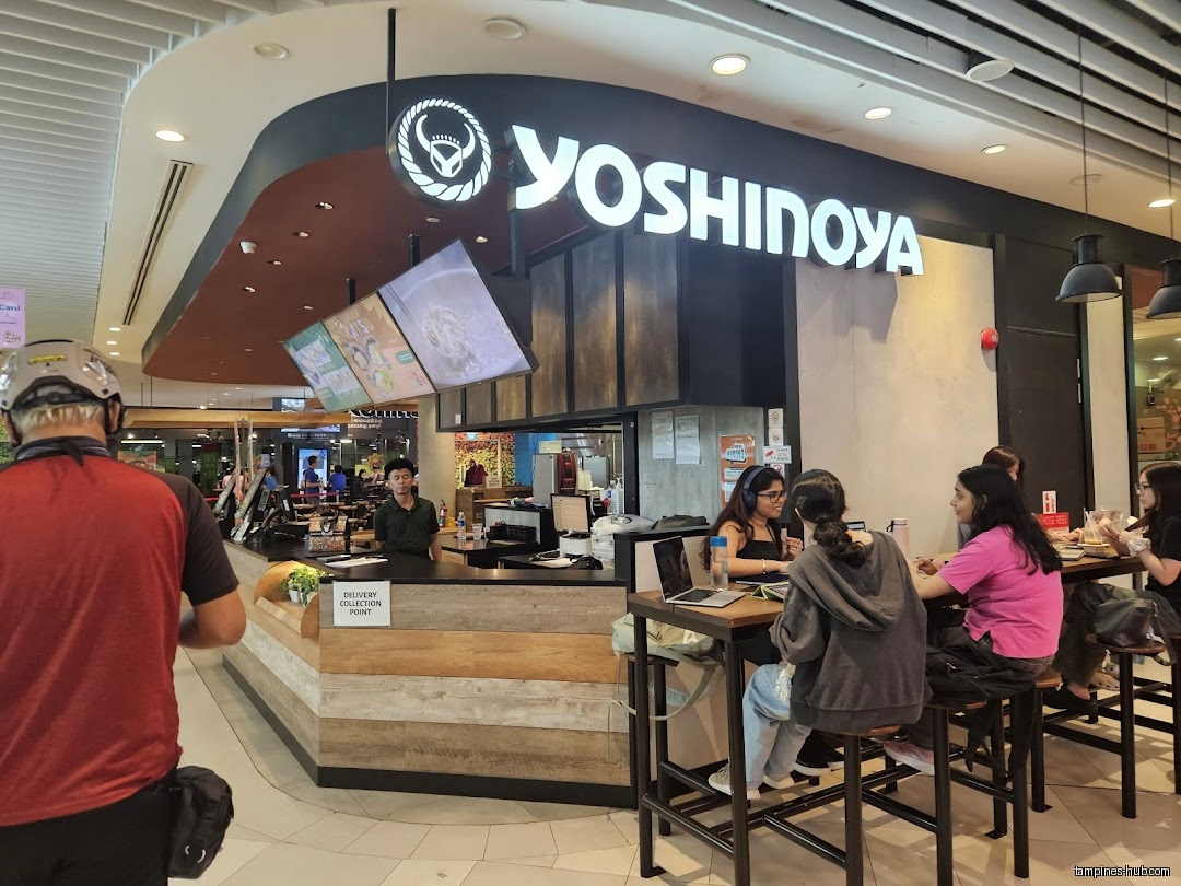 Yoshinoya restaurant front with customers dining and a delivery person approaching.