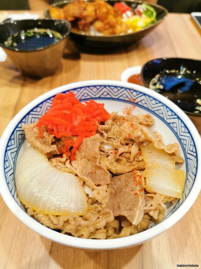 A bowl of beef rice with red ginger and onions is shown.